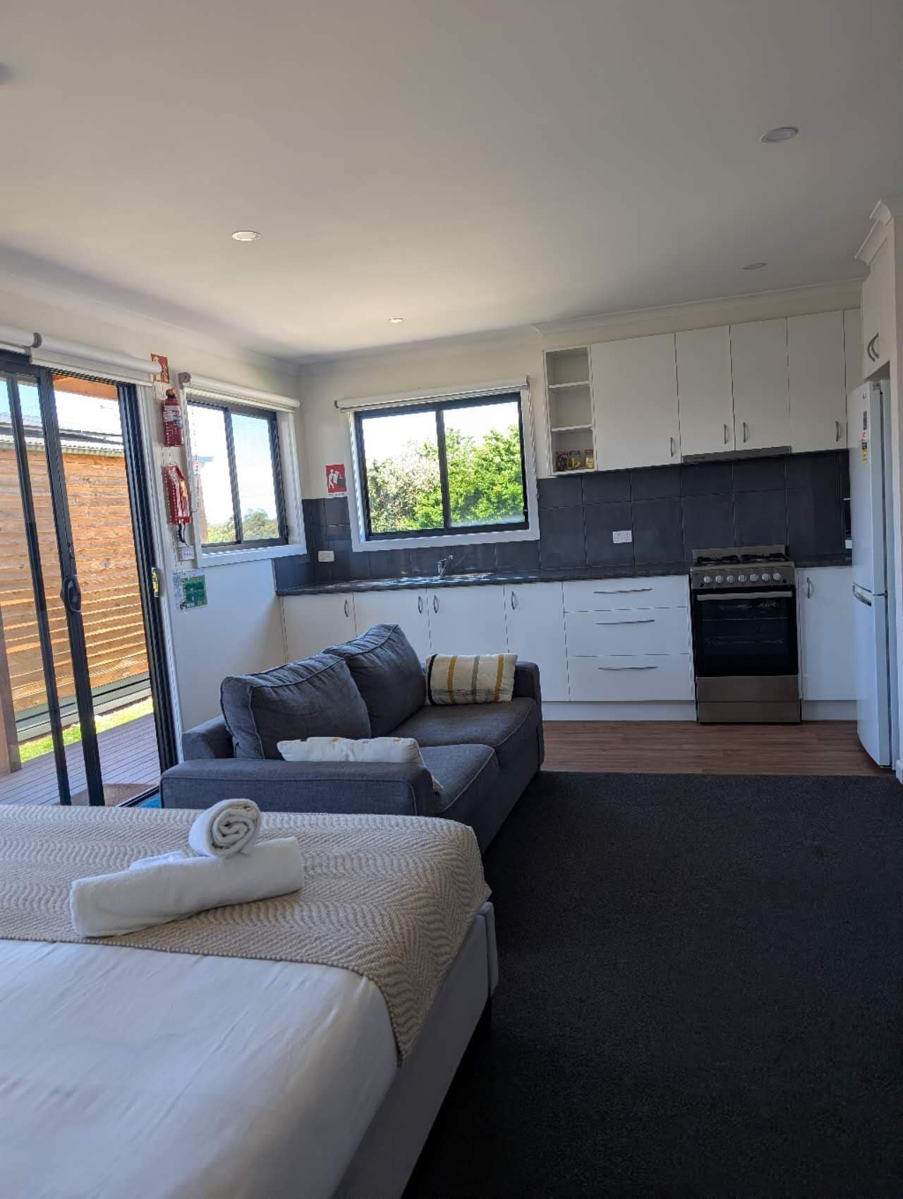 A modern bedroom with a large bed, a sofa, and a dining area with a stove.