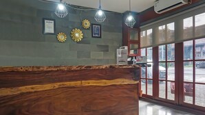 A reception area with a wooden reception desk, framed certificates, and decorative wall pieces. - Hotel O Bogor Guest House (Bogor)