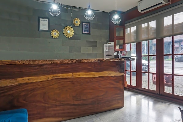 A reception area with a wooden reception desk, framed certificates, and decorative wall pieces. - Hotel O Bogor Guest House (Bogor)