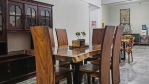 A dining area with a wooden table and chairs, a cabinet with glass doors, and a water dispenser on the wall. - Hotel O Bogor Guest House (Bogor)