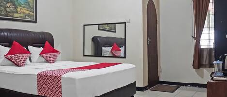 A hotel room with a bed, a mirror, a door, and a window with curtains.