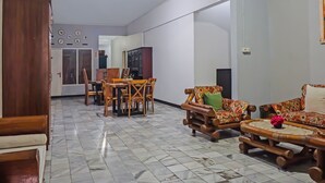 A spacious living area with a tiled floor, wooden furniture, and a dining set. - Hotel O Bogor Guest House (Bogor)