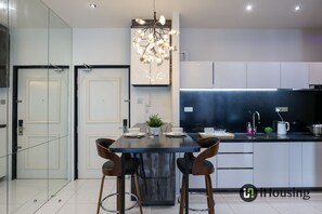 Una cocina moderna con una isla central, taburetes de bar, una lámpara colgante y horno empotrado.