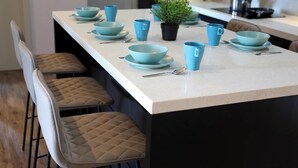 A kitchen island with blue bowls and cups, a potted plant, and bar stools. - Atlantis Residence Premium By I Housing (Malacca City)