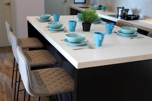 A kitchen island with blue bowls and cups, a potted plant, and bar stools.