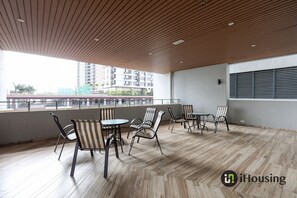 Ein geräumiger Balkon mit Holzboden, mehreren Stühlen und Tischen mit Blick auf die Stadt.