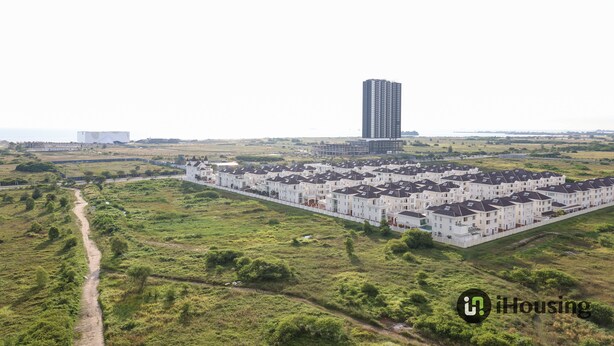 A residential area with a row of white townhouses and a tall building in the background.