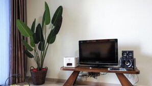 A flat-screen TV on a wooden stand with a speaker and a white device on it. - Atlantis Residence Premium By I Housing (Malacca City)