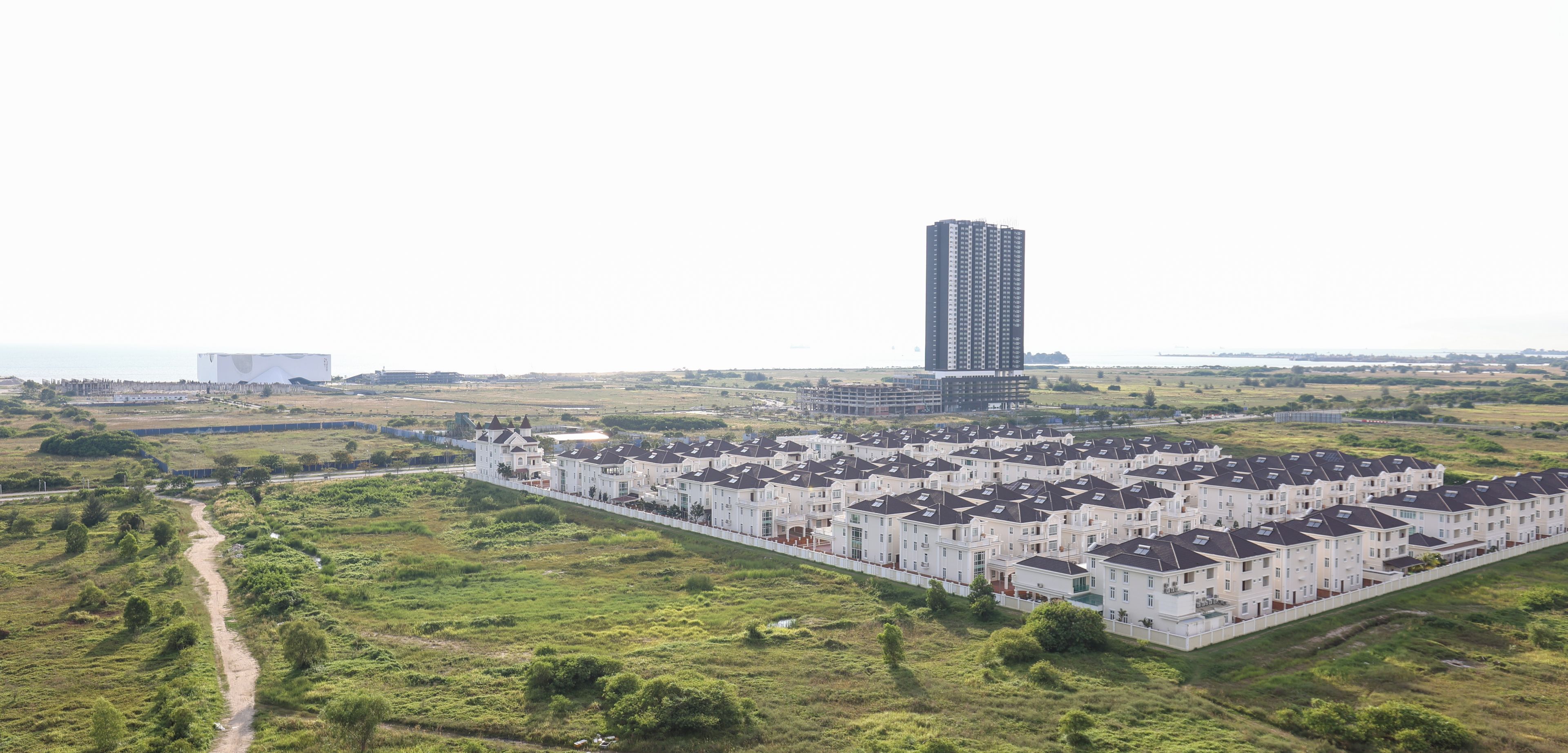A residential area with a row of white townhouses and a tall building in the background.