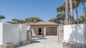 Un bâtiment en pierre avec un toit en tuiles, une entrée pavée et une antenne parabolique.