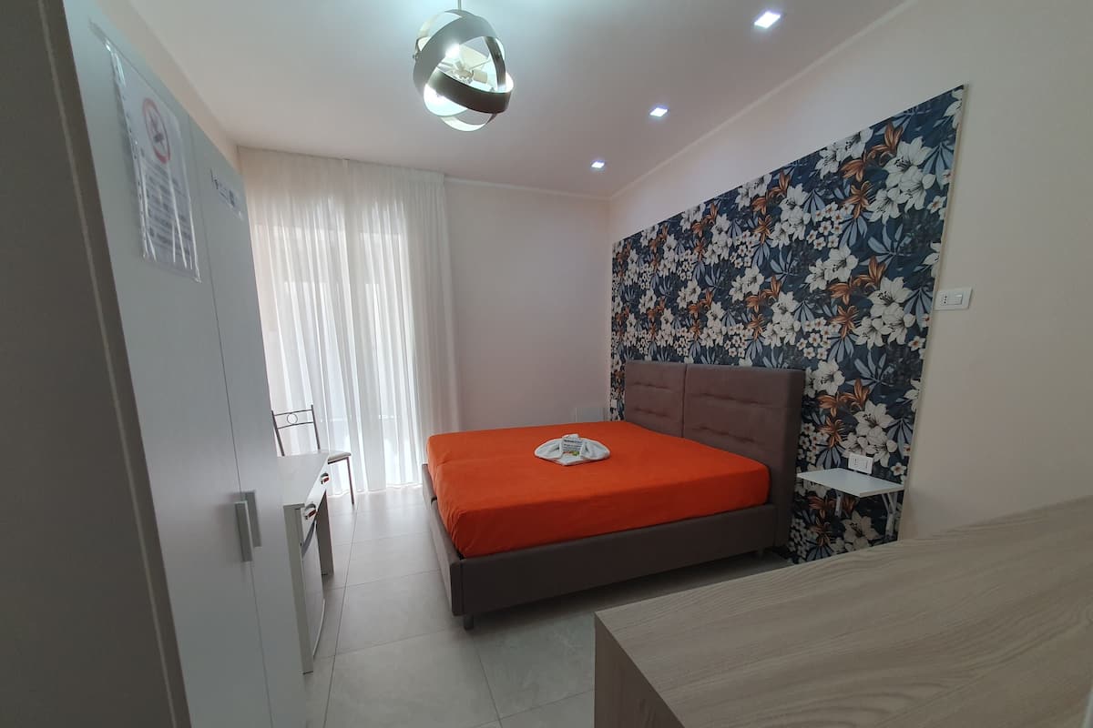 A bedroom with a bed, a desk, and a chair.