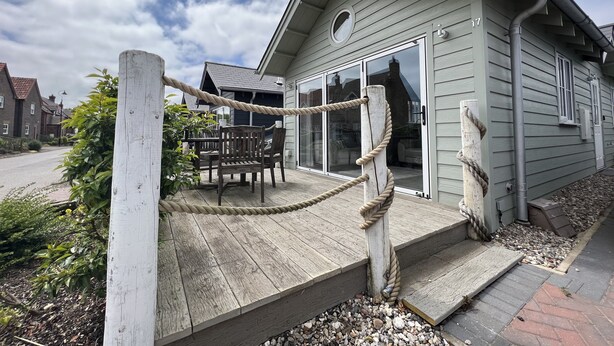 A wooden deck with a rope barrier, a dining table, and chairs.
