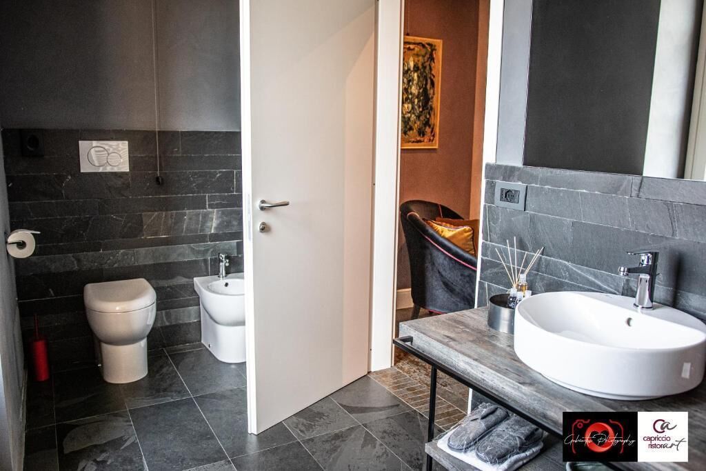A modern bathroom with a toilet, bidet, and a large sink with a wooden countertop.
