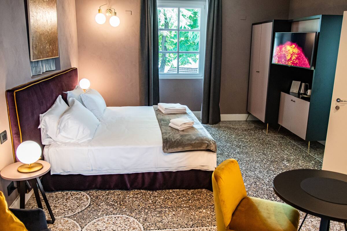 Ein Hotelzimmer mit Bett, Fernseher, kleinem Tisch und Stuhl.