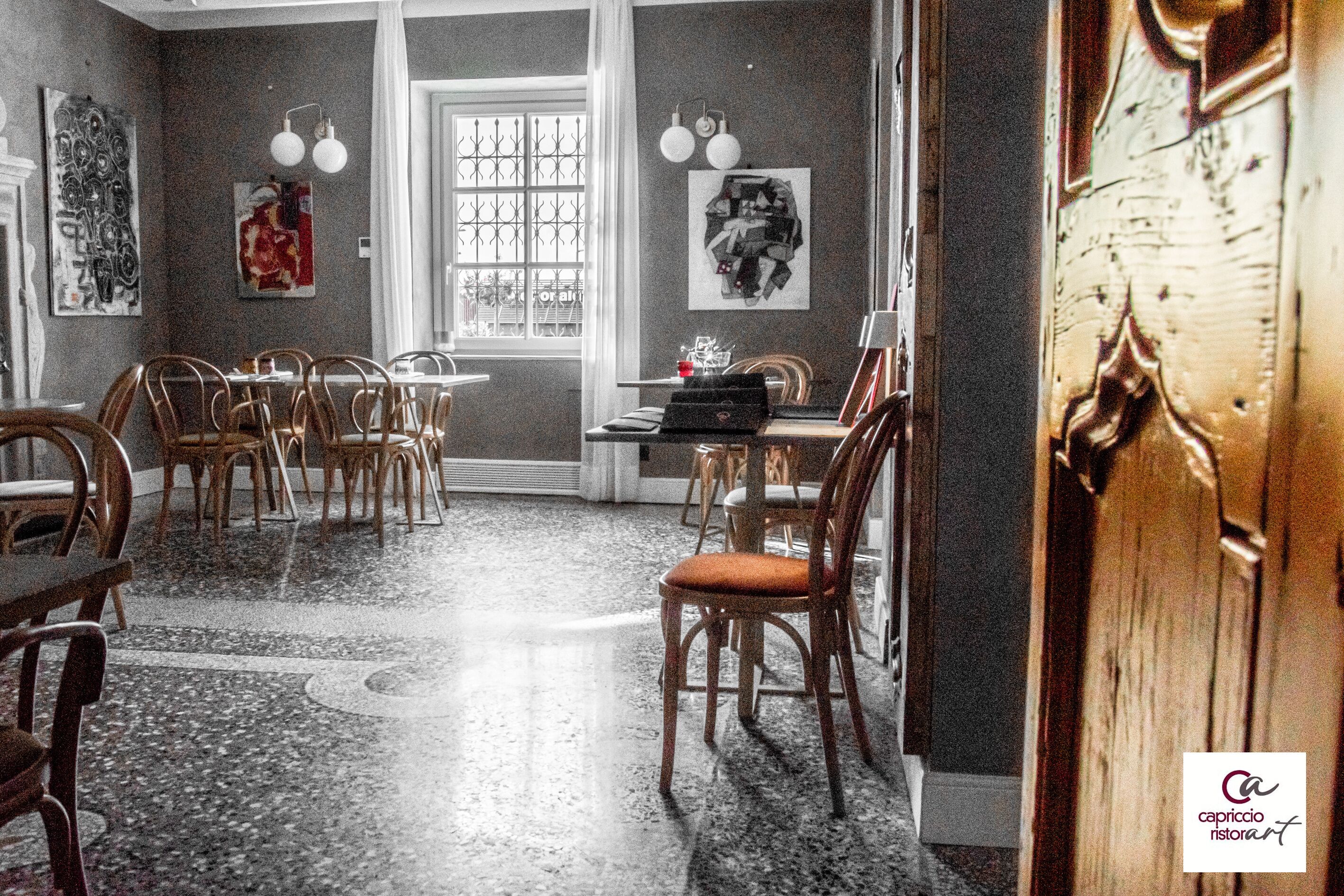 A dining area with wooden chairs and tables, a patterned floor, and artwork on the walls.