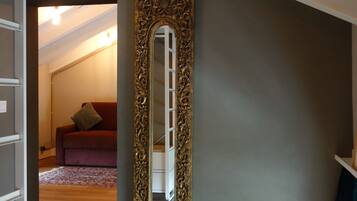 Una habitación con un espejo grande, un sofá rojo y suelo de madera.