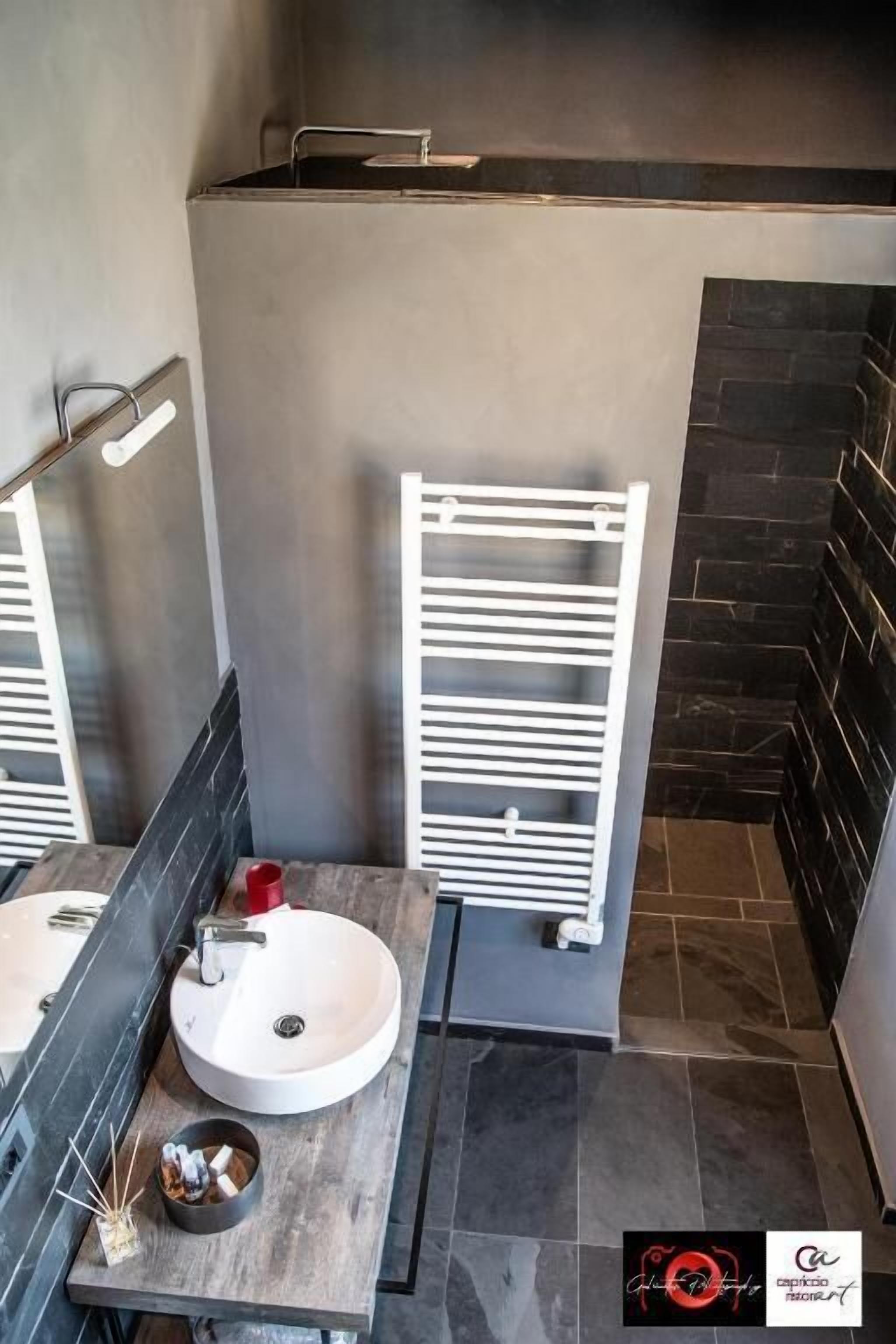 Uma casa de banho moderna com uma pia redonda, um porta-toalhas branco e um espelho.