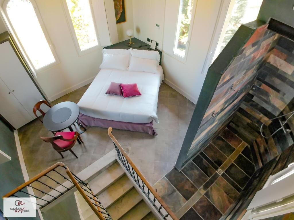 Un dormitorio con cama, una silla, una mesita y una escalera.