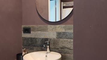 A bathroom with a round mirror, a white sink, and a towel rack.