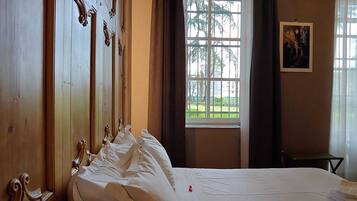 Ein Hotelzimmer mit einem großen Bett, einem Holzschrank, einem Fenster mit Vorhängen und einem gerahmten Bild an der Wand.