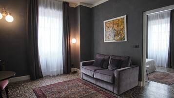 A modern living room with a grey sofa, a patterned rug, and a large abstract painting on the wall.