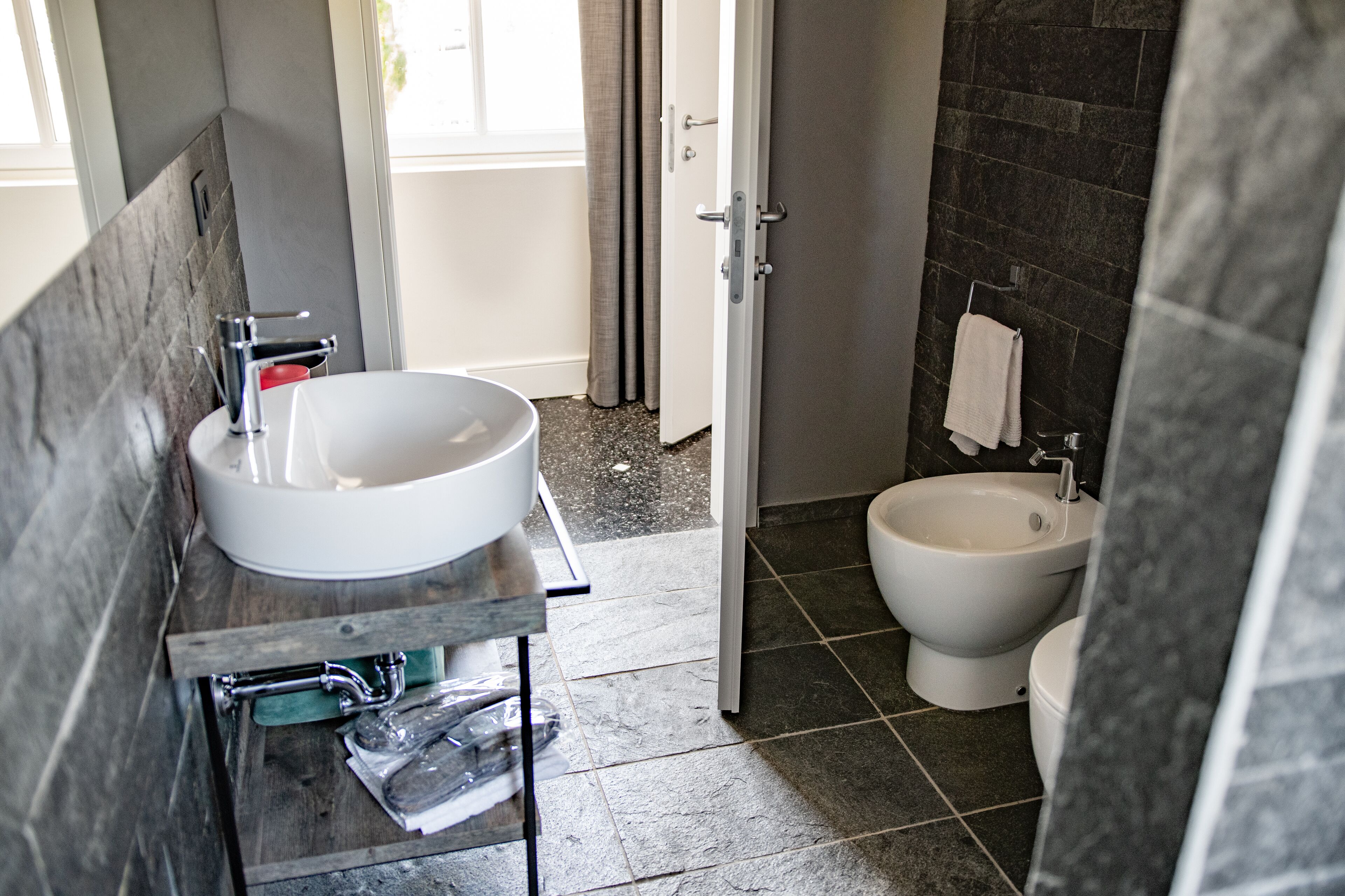 A bathroom with a large white sink, a bidet, and a mirror.