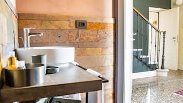 Un bagno con parete in pietra, un lavandino e uno specchio.
