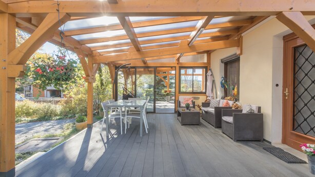 Un patio abrité avec une pergola en bois, des sièges d’extérieur et une vue sur le jardin.
