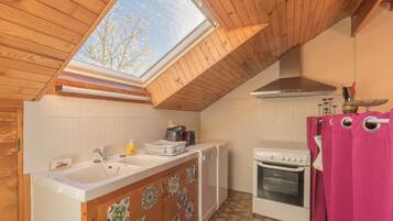 A kitchen with a skylight, white cabinets, a stove, and a dishwasher.