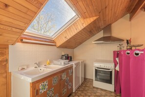 Une cuisine dotée d’une lucarne, de meubles blancs, d’une cuisinière et d’un lave-vaisselle.