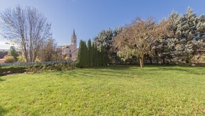 Une zone herbeuse avec des arbres et, au loin, un bâtiment doté d’un clocher.