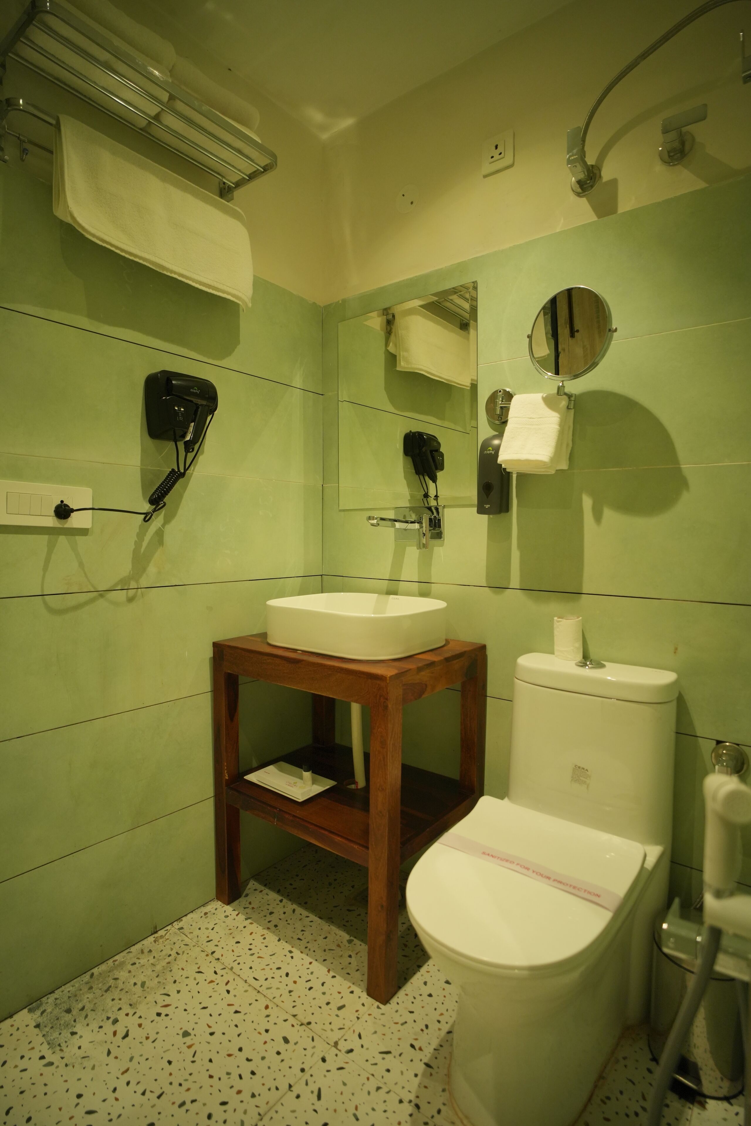 A bathroom with a wooden vanity, a white sink, a toilet, and a mirror.