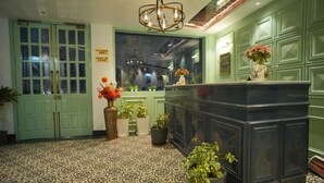 A room with a patterned floor, a reception desk, a green door, and several potted plants. - Oakhill Resort (Kasauli)