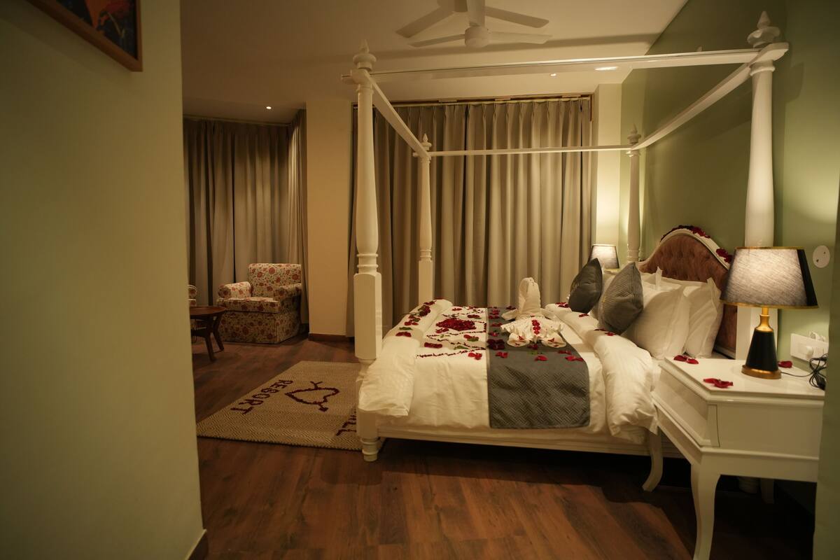 A four-poster bed with a canopy, a bedside table with a lamp, and a chair in a hotel room.
