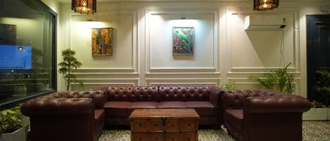 A lobby with a leather sectional sofa, a patterned floor, and artwork on the walls.