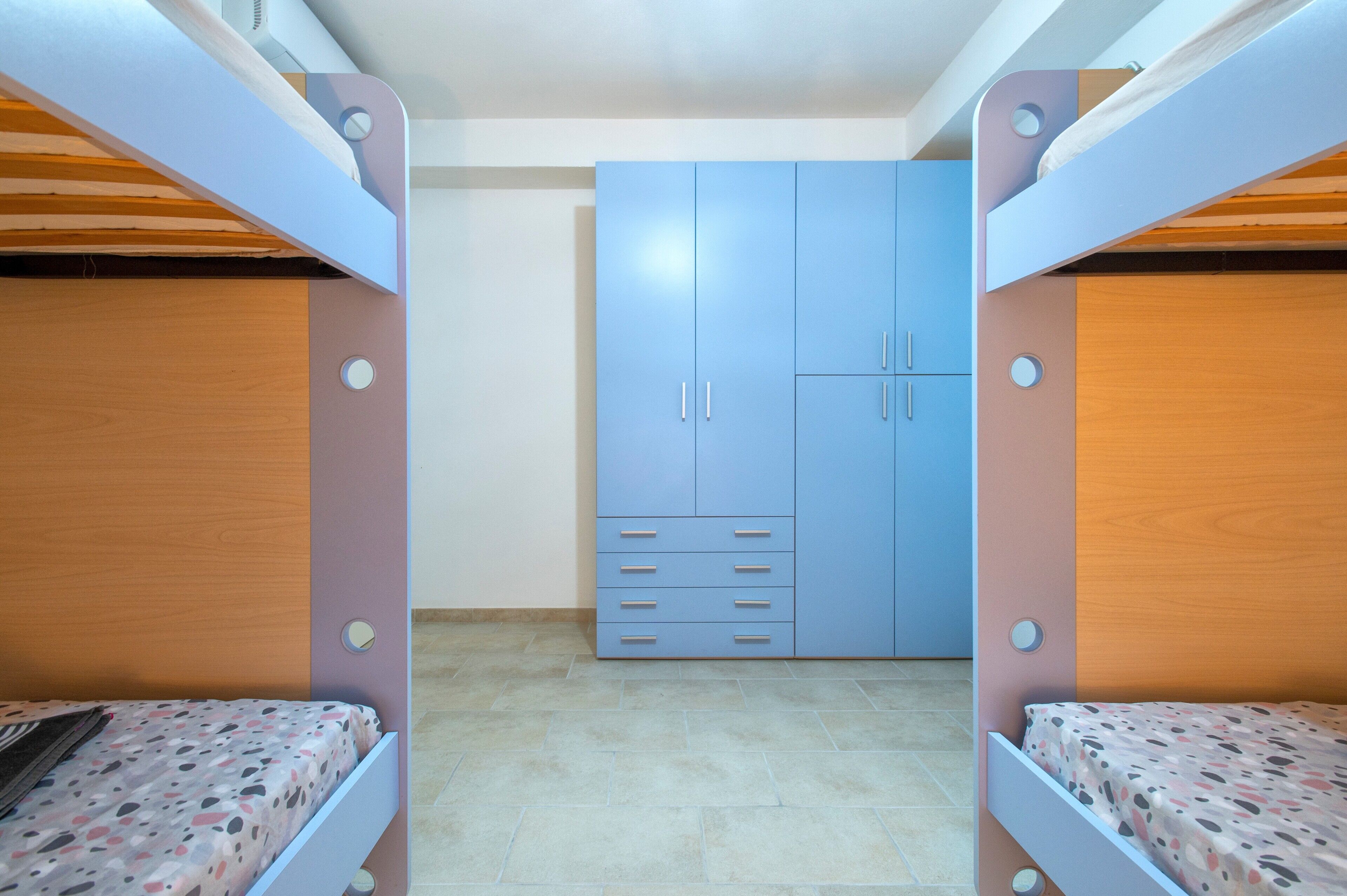 Una habitación con literas, un armario y suelo de baldosas.