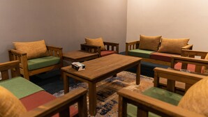 Une pièce chaleureuse, meublée de meubles en bois, dont des chaises et un canapé, disposés autour d’une table centrale.