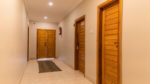 Un couloir avec des portes en bois, un extincteur et un tapis sur le sol.
