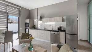 Eine moderne Küche mit Geschirrspüler, Kühlschrank und Essbereich mit Tisch und Stühlen.