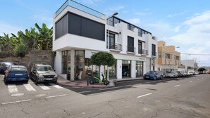 Ein modernes Gebäude mit großen Fenstern, einem Balkon und geparkten Autos auf der Straße.