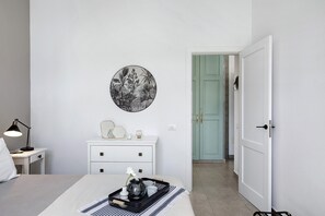 Une chambre à coucher comprenant un lit, une table de chevet, une lampe, une commode et une œuvre d’art accrochée au mur.
