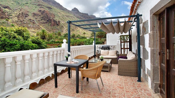 A terrace with a table, chairs, and a sofa, overlooking a mountainous landscape. - Vacation Home "La Casa Nueva" with Mountain View, Whirlpool & Wi-Fi (Fataga)