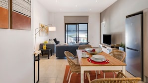 Una sala de estar moderna con sofá, mesa de comedor, sillas y televisor.