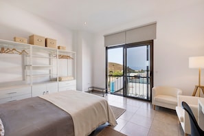 Une chambre à coucher comprenant un lit, une armoire, une chaise, une lampe et un balcon avec vue.