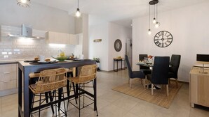 A modern kitchen with a central island, bar stools, and pendant lighting.
