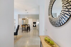 Une cuisine moderne avec un coin repas, un miroir rond et une table en bois sur laquelle sont posées des pommes.