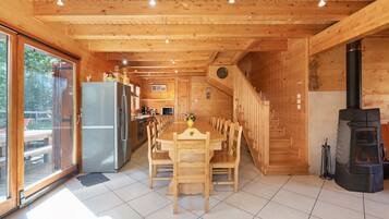 A wooden interior with a dining area, kitchen, and a fireplace.