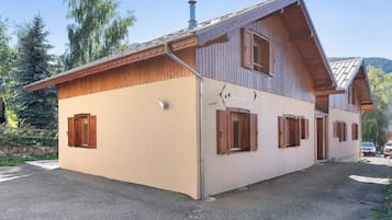 Ein zweigeschossiges Holzhaus mit einem geneigten Dach, einem Schornstein und Holzläden an den Fenstern.
