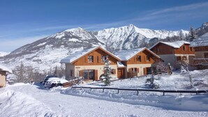 Une station de montagne enneig ée, avec des chalets en bois et un ciel d’un bleu limpide.