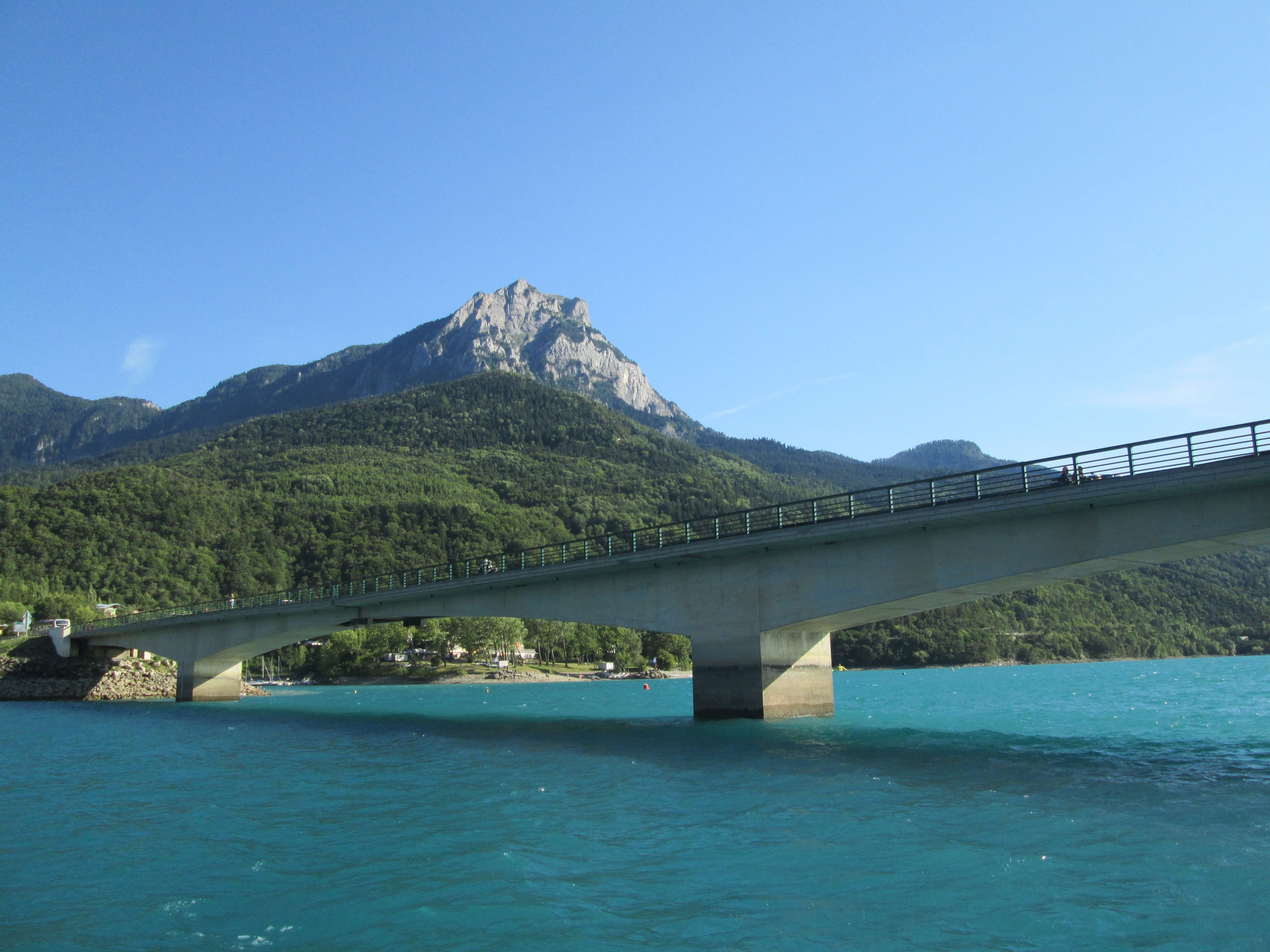 A bridge over a body of water with a mountain in the background.